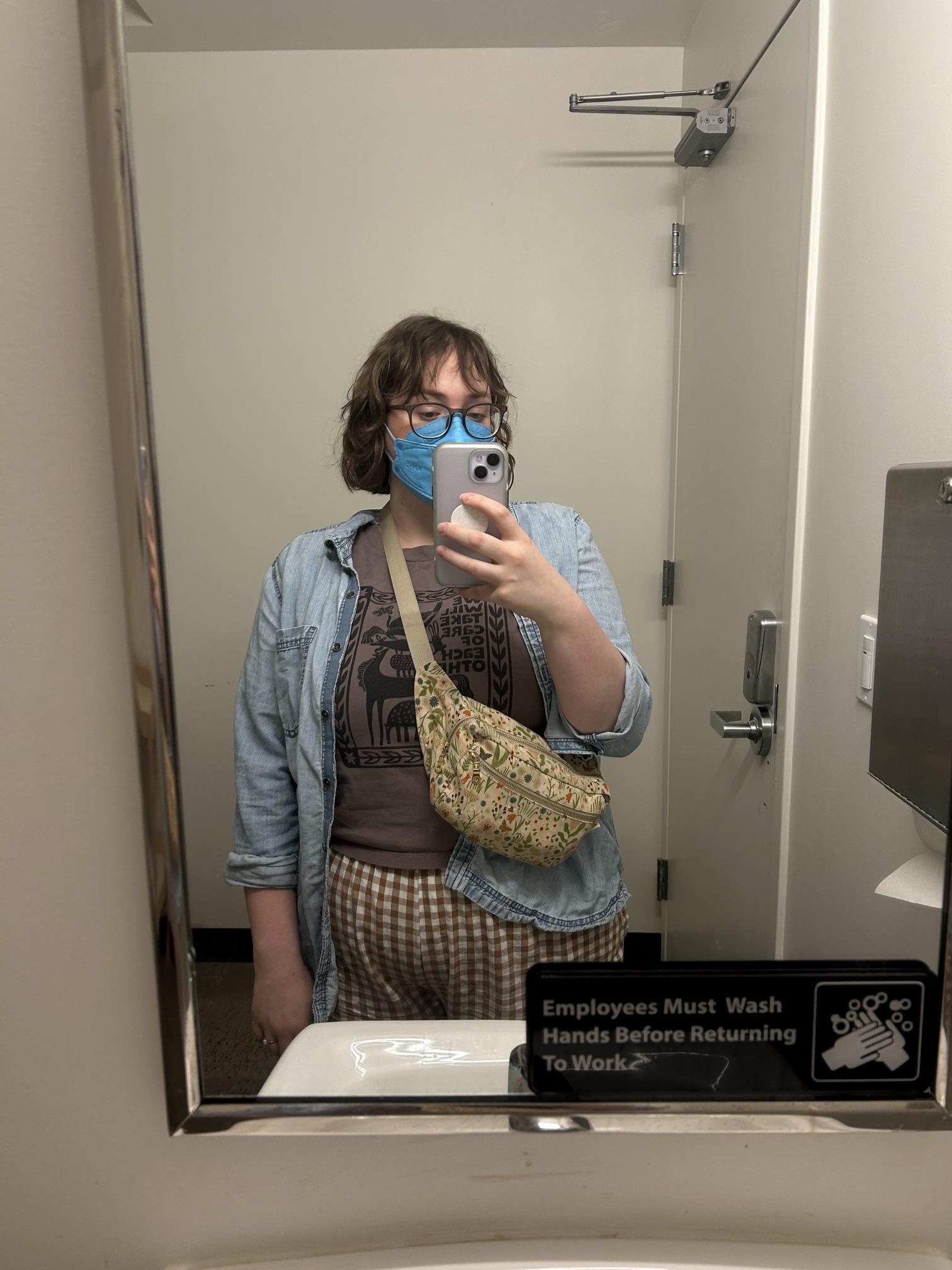 A woman wears a medical mask and carries her fanny pack crossbody.