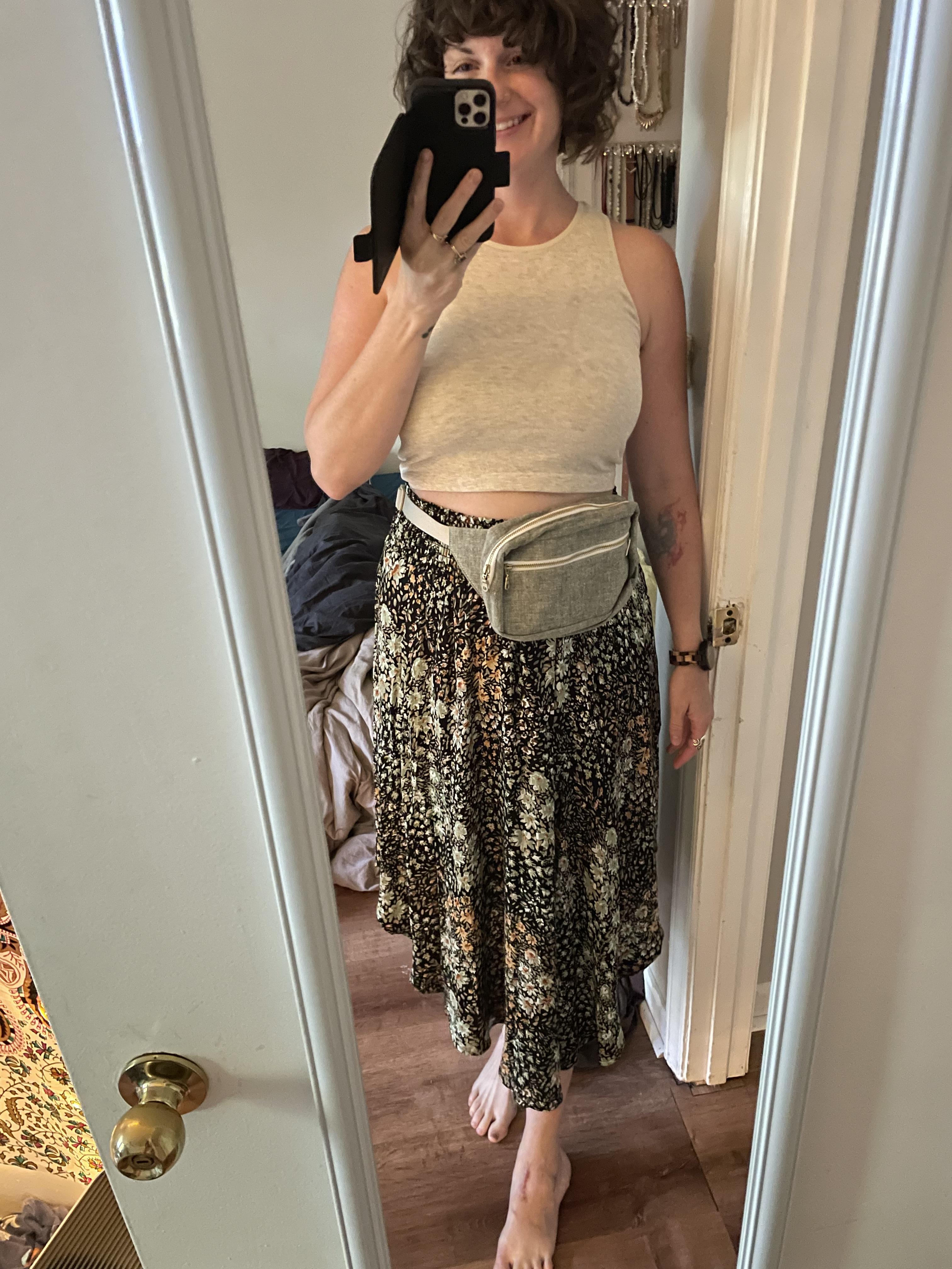 A white, straight sized woman wears her fanny pack as a belt, over her long skirt.